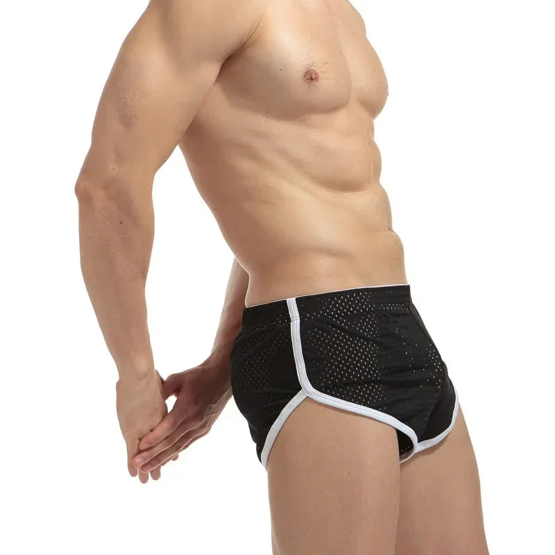 Man wearing black swim briefs with white trim on a white background