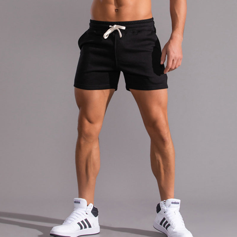 Person wearing black shorts and white sneakers on a gray background