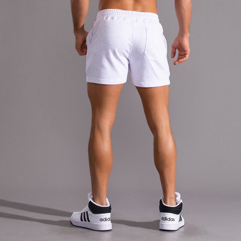 Person wearing white shorts and Adidas shoes on a gray background