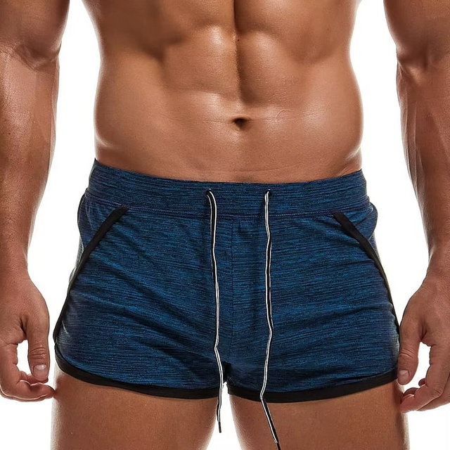 A close-up of a man's lower torso wearing heathered blue athletic shorts with black side trim and white drawstrings, against a plain white background.