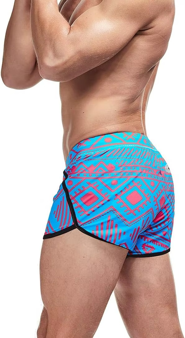 A close-up side view of a man wearing bright blue swim trunks with a pink geometric pattern and black trim, against a plain white background.