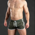 Man wearing green athletic shorts with white drawstring on a dark background