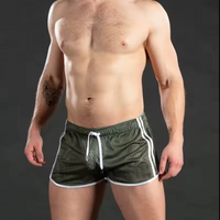 Man wearing green athletic shorts with white drawstring on a dark background