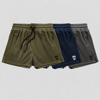 Three pairs of athletic shorts in olive green, navy blue, and gray, arranged in a row against a light gray background. Each pair features a drawstring waist, side pockets, and a small skull logo near the hem.