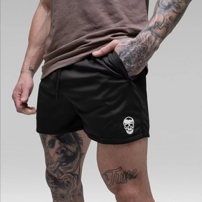 Person wearing black shorts with a skull logo on a plain background