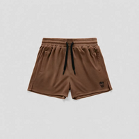 A pair of brown athletic shorts with a black drawstring and a small black logo on the lower left leg, displayed flat against a light gray background.