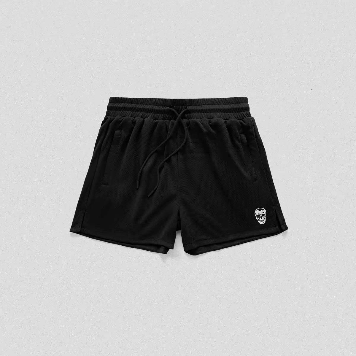 Black athletic shorts with a drawstring waist and a small white skull logo on the lower left leg, shown flat on a light gray background.